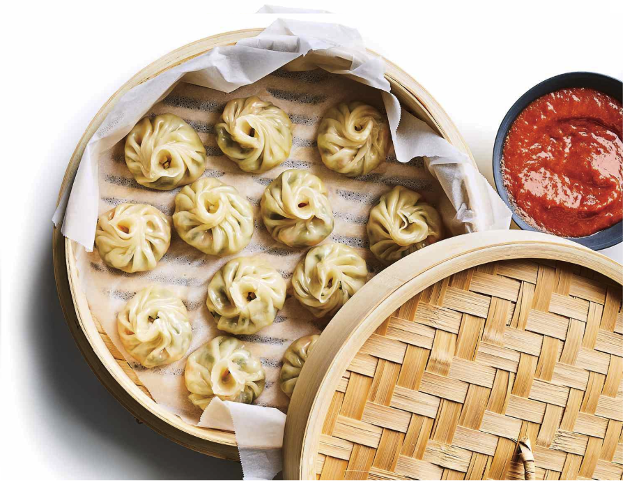 Steaming chicken momos in a traditional bamboo basket