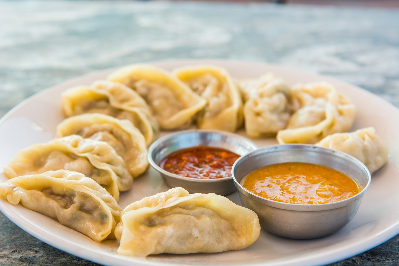 Close up of perfectly cooked chicken momos with dipping sauce
